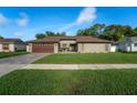 Well-maintained single-story home with a brick driveway, lush grass and mature landscaping at 12542 Idaho Woods Ln, Orlando, FL 32824