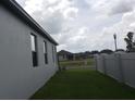 View of the side yard with healthy grass and a white fence at 1292 Hilltop Pl, St Cloud, FL 34772