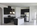 Modern kitchen with stainless steel appliances, dark cabinets, granite countertops, and a center island at 1292 Hilltop Pl, St Cloud, FL 34772