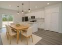 Open-concept kitchen and dining area featuring white cabinets, stainless steel appliances, and pendant lighting at 2580 Gallardia Dr, Lake Wales, FL 33898