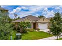 Exterior shot of home with manicured lawn, two-car garage and verdant plantings at 2726 Harmonia Hammock Rd, Harmony, FL 34773