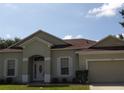 Inviting single-story home with a light-colored exterior, well-manicured lawn, and an attached garage at 3074 Bay Laurel N Cir, Kissimmee, FL 34744