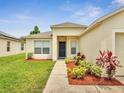 Inviting entryway of a well-maintained home with a tidy walkway, complemented by vibrant landscaping at 3274 Hunters Chase Loop, Kissimmee, FL 34743