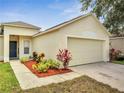Attached two-car garage with a paved driveway and colorful landscaping at 3274 Hunters Chase Loop, Kissimmee, FL 34743