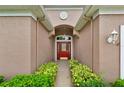 Front door with red door, side lights and transom window with an arched ceiling and decorative plants at 4065 Kingsley St, Clermont, FL 34711