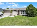 Inviting home exterior with a green lawn, mature landscaping, and a two-car garage at 440 Peppermill Cir, Kissimmee, FL 34758