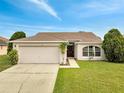 Charming single-story home featuring a manicured lawn, a two-car garage, and an inviting front entrance at 440 Peppermill Cir, Kissimmee, FL 34758