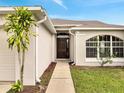 Inviting front entrance with a dark wood door, beautiful arched window, and a well-maintained landscape at 440 Peppermill Cir, Kissimmee, FL 34758