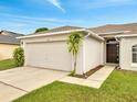 Single story home featuring a two-car garage, well-manicured lawn, and an inviting front entrance at 440 Peppermill Cir, Kissimmee, FL 34758
