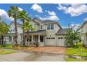 Charming two-story home featuring lush landscaping, a brick driveway, and a three-car garage at 4952 Creekside Park Ave, Orlando, FL 32811