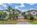 An elevated view of a landscaped two-story home with a brick driveway and a three-car garage at 4952 Creekside Park Ave, Orlando, FL 32811