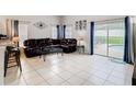 Spacious living room with tiled floors, comfortable leather seating, and sliding glass doors leading to the pool area at 824 Bloomingdale Dr, Davenport, FL 33897