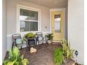 Cozy front porch adorned with brick pavers, comfortable seating, potted plants, and a bright yellow front door at 1895 Spring Shower Cir, Kissimmee, FL 34744