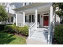 Inviting front porch featuring classic columns, white railings, and a cheerful red front door at 1236 Aquila Loop, Celebration, FL 34747