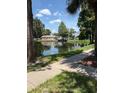 Scenic view of a pond reflecting nearby buildings, surrounded by lush greenery and walking paths at 1608 Columbia Arms Cir # 126, Kissimmee, FL 34741