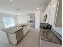 Open kitchen featuring an island with granite countertops, stainless steel appliances, and modern lighting at 2479 White Lilly Dr, Kissimmee, FL 34747
