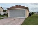 Exterior shot of screened garage, brick-paved driveway, and lush green lawn at 2646 Quarterdeck Ct, Kissimmee, FL 34743