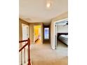 Upstairs hallway with neutral colored carpet and walls leads to a bedroom and bathroom at 4368 Fox Glen Loop, Kissimmee, FL 34746