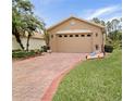 Charming single-story home featuring a brick driveway, attached garage, and manicured lawn at 516 Millifiora Ln, Kissimmee, FL 34759