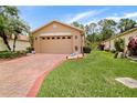 Well-maintained home with a brick driveway, verdant lawn, and a neutral-toned exterior at 516 Millifiora Ln, Kissimmee, FL 34759