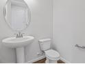 Clean half bathroom featuring a pedestal sink, sleek fixtures, toilet, and wood-look flooring for a modern touch at 660 Summit River Dr, Apopka, FL 32712