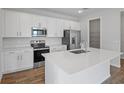 Modern kitchen with white cabinets, stainless steel appliances, quartz countertops, and a central island at 660 Summit River Dr, Apopka, FL 32712