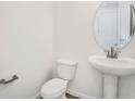 Clean, half bathroom showcasing a pedestal sink, round mirror, and modern fixtures at 675 Summit River Dr, Apopka, FL 32712