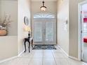 Bright foyer featuring tile flooring, neutral walls, decorative console table, and a front door with transom window at 116 Westport Ln, Davenport, FL 33896