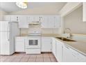 Bright kitchen featuring white cabinets, appliances, and tile flooring at 2907 Prince Oak Ct, St Cloud, FL 34769