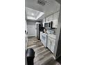 Compact kitchen with white cabinets, skylight, wood-look flooring, and stainless steel appliances at 4341 Aqua Vista Dr # A, Orlando, FL 32839