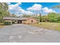 Spacious driveway leads to a home featuring a brick facade and an American flag, set amidst lush greenery and a carport at 4410 Mildred Bass Rd, St Cloud, FL 34772