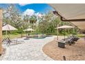 Backyard with in-ground pool, patio with brick pavers, lounge chairs and umbrellas surrounded by mature shade trees at 4410 Mildred Bass Rd, St Cloud, FL 34772