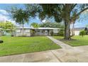 Charming single-story home featuring a metal roof, lush landscaping, and a brick-paved walkway at 612 Lakeshore Blvd, Kissimmee, FL 34744