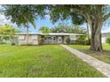 Charming single-story home boasts lush lawn, mature trees, and inviting walkway to the front door at 612 Lakeshore Blvd, Kissimmee, FL 34744