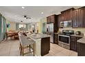 Open kitchen with stainless steel appliances, granite countertops, island with barstool seating, and dark wood cabinetry at 7613 Brookhurst Ln, Kissimmee, FL 34747