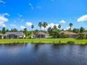 Water view of backyard featuring several screened lanais, a manicured lawn and various mature palm trees at 777 Glendora Road, Poinciana, FL 34759