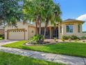 Charming single-story home featuring a well-manicured lawn, mature palm trees, and a brick-paved driveway at 777 Glendora Road, Poinciana, FL 34759