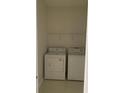 A compact laundry room with a side-by-side washer and dryer on white tile floors at 808 Massy Ct, Kissimmee, FL 34759