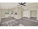 Open-concept living area with gray wood floors, neutral paint, and a view into the kitchen at 3 Trophy Ln, Kissimmee, FL 34759