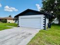 Attached two-car garage with white door and well manicured lawn at 406 Long Dr, Kissimmee, FL 34759