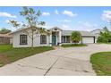 Charming single-story home featuring a teal front door, attached garage, and manicured landscaping at 4407 Lake Trudy Dr, St Cloud, FL 34769