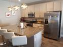 Stylish kitchen featuring a granite island with bar stool seating, stainless steel appliances, and modern cabinetry at 1222 Yorkshire Ct, Davenport, FL 33896