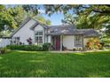 Charming single-story home with a well-manicured lawn, garden, and a red front door at 2225 Maryday Ct, Orlando, FL 32812