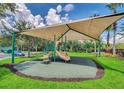 Community playground featuring a covered play structure with slides, surrounded by green grass and trees at 3162 Rodrick Cir, Orlando, FL 32824