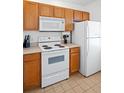 Efficient kitchen featuring white appliances and wood cabinets, ideal for cooking and storage at 4014 Santa Maria Dr # 101, Kissimmee, FL 34741
