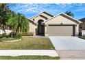 Charming home featuring a manicured lawn, arched entry, and a two-car garage at 7922 Elmstone Cir, Orlando, FL 32822