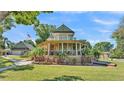 Charming home with a large porch, mature trees, lush lawn, and detached garage at 822 W Patterson St, Lakeland, FL 33803