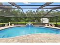 Relaxing pool area with a screened enclosure, waterfall feature, and plenty of room for entertaining at 911 Mendoza Ln, Kissimmee, FL 34758