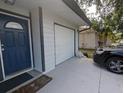 A front door with sidelight enters into a view of an attached garage with an adjacent dark colored car in driveway at 946 Delano Ct, Kissimmee, FL 34758