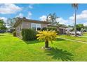 Side view of the home showcasing the well-maintained lawn and mature tropical landscaping at 1566 Providence Blvd, Deltona, FL 32725